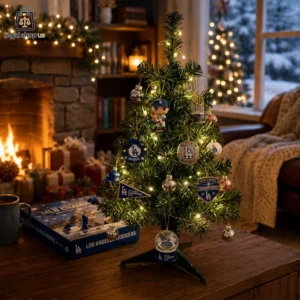 A small Christmas tree decorated with Los Angeles Dodgers ornaments near a cozy fireplace.