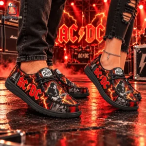 Person wearing AC/DC themed Hey Dude slip-on shoes on a concert stage