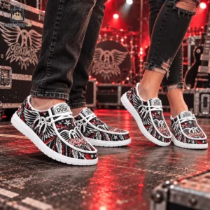 Two people wearing Aerosmith branded Hey Dude shoes on a concert stage