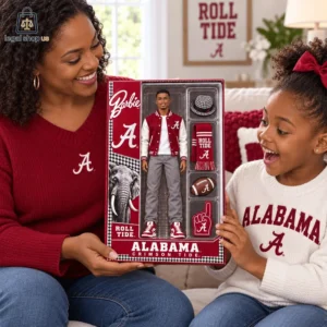 A woman and a young girl excitedly holding an Alabama Crimson Tide Ken doll in packaging.